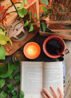 An open e-book on a cozy desk surrounded by plants and a warm cup of tea.