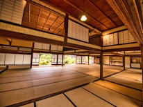Interior view of a warm, traditional Japanese room with wooden beams and shoji screens.
