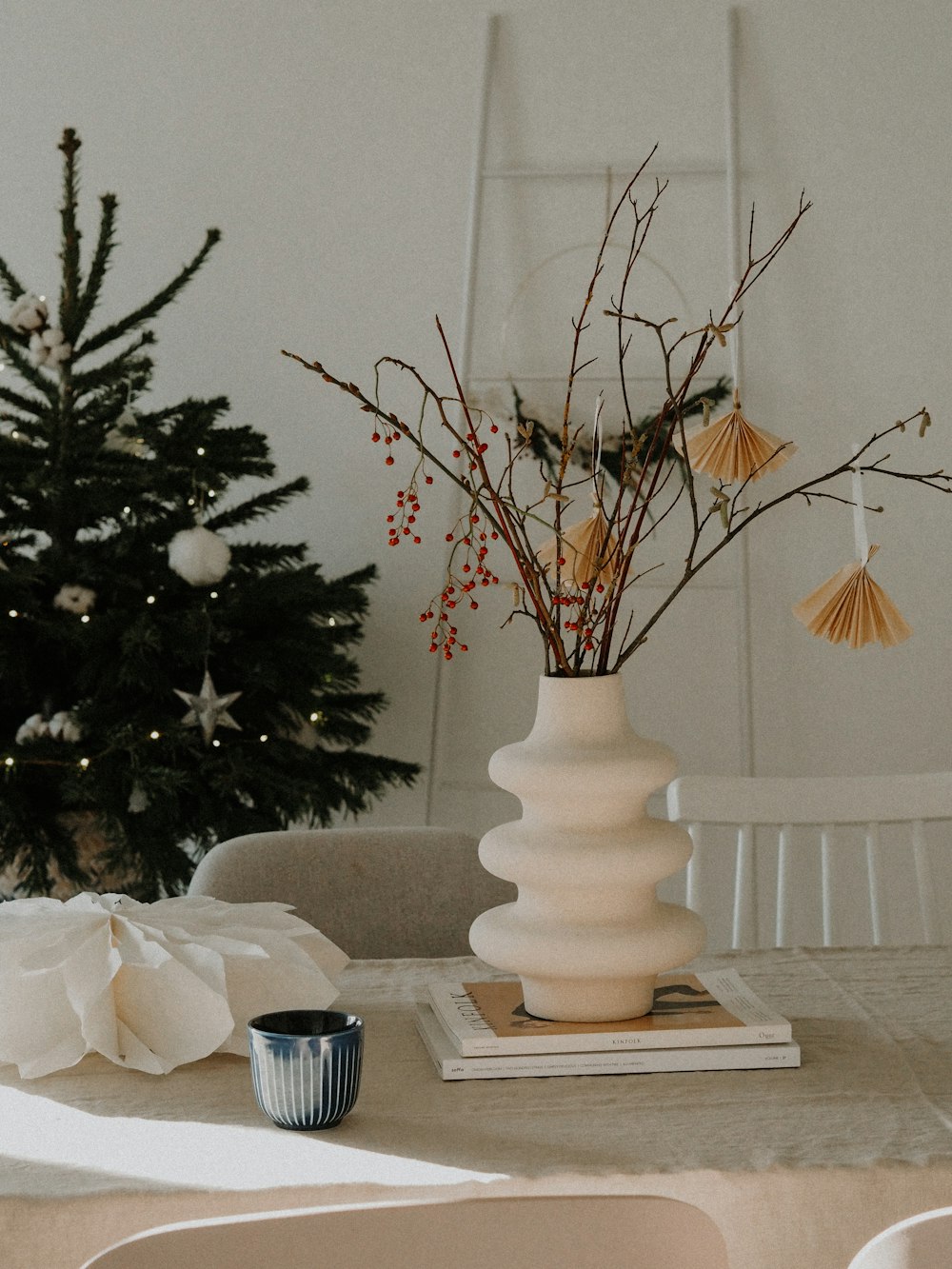 weiße Keramikvase mit roten Blumen auf dem Tisch