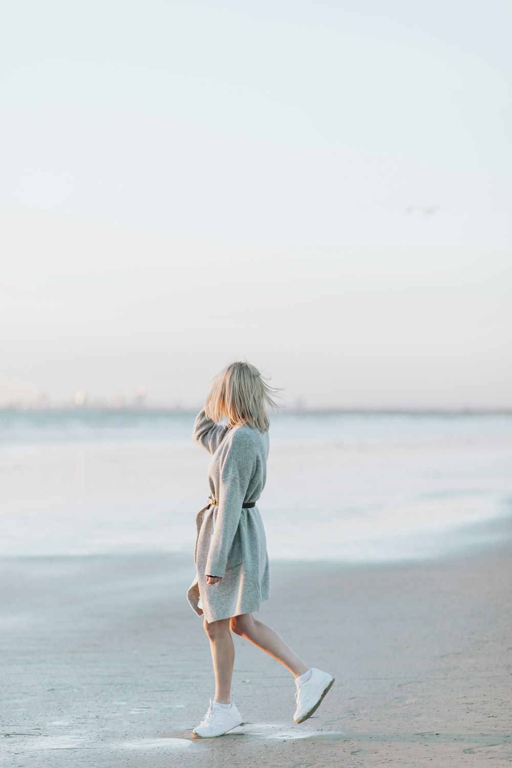 낮 동안 해변에 서 있는 하얀 드레스를 입은 소녀