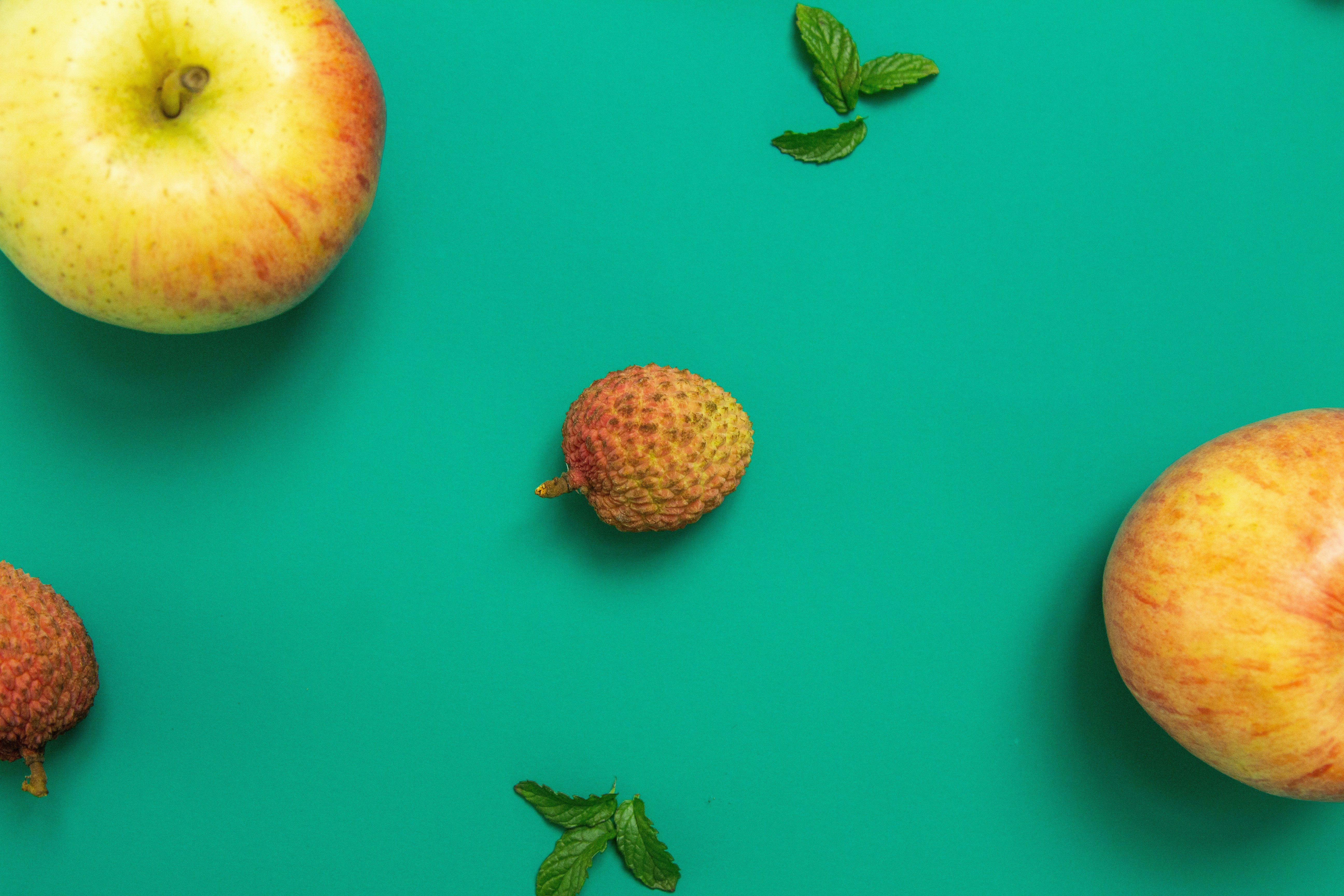 two red and yellow apple fruits on pink surface
