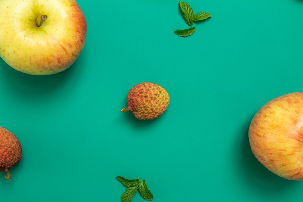 two red and yellow apple fruits on pink surface