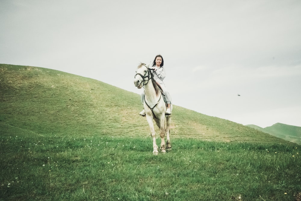 white horse running on green grass field during daytime