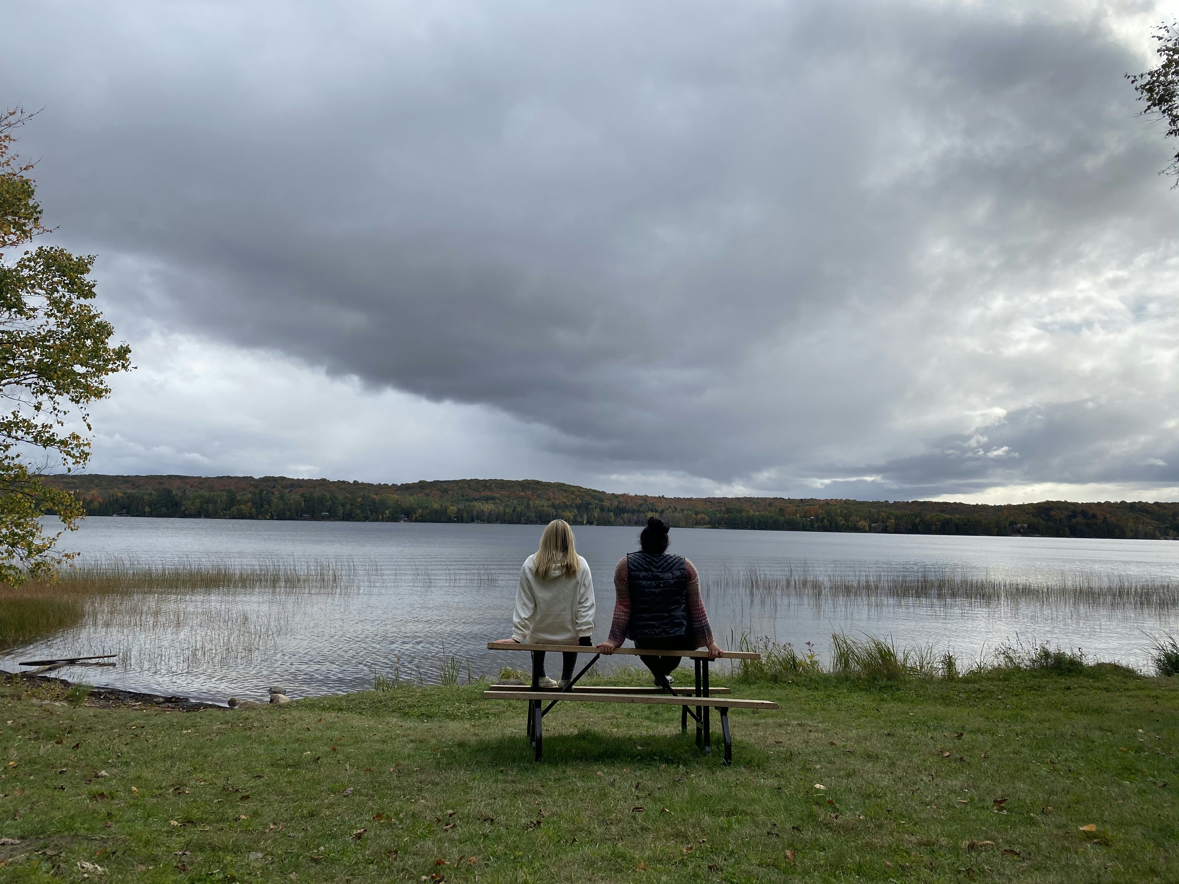 man in black shirt sitting on black chair near body of water during daytime