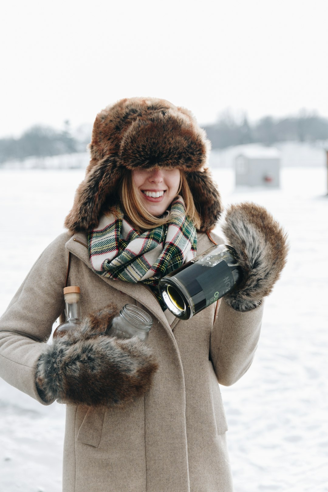 woman in brown fur coat holding black ceramic mug