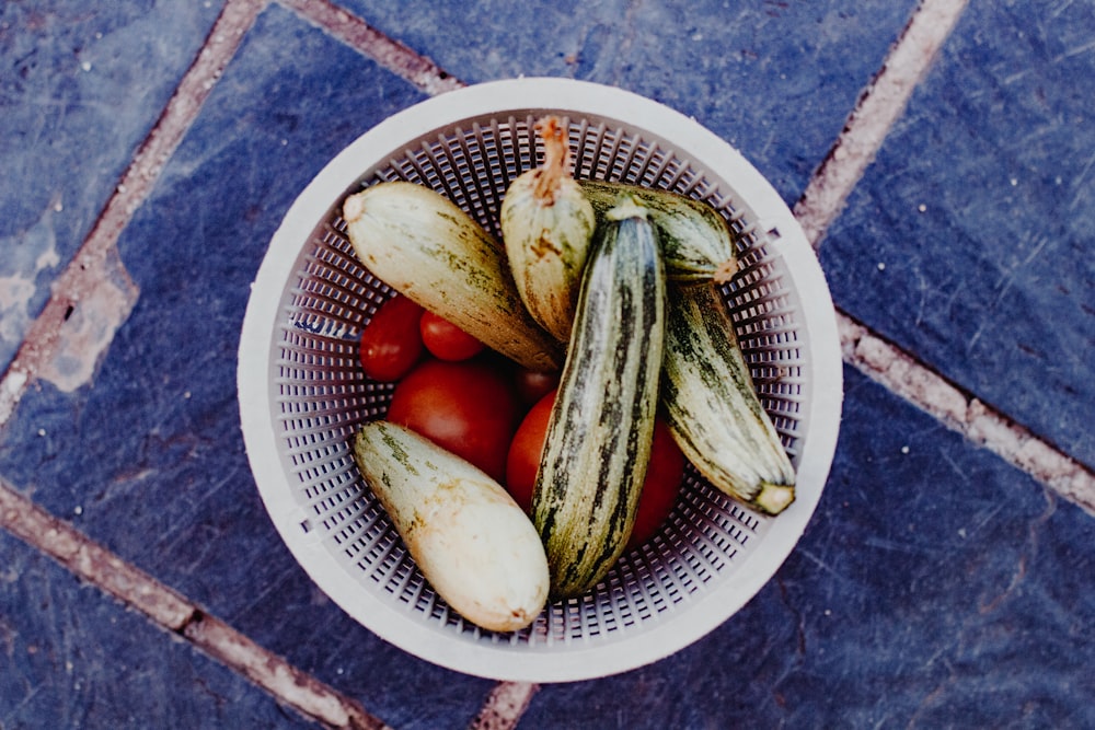 green cucumber and red tomato on white and blue ceramic bowl