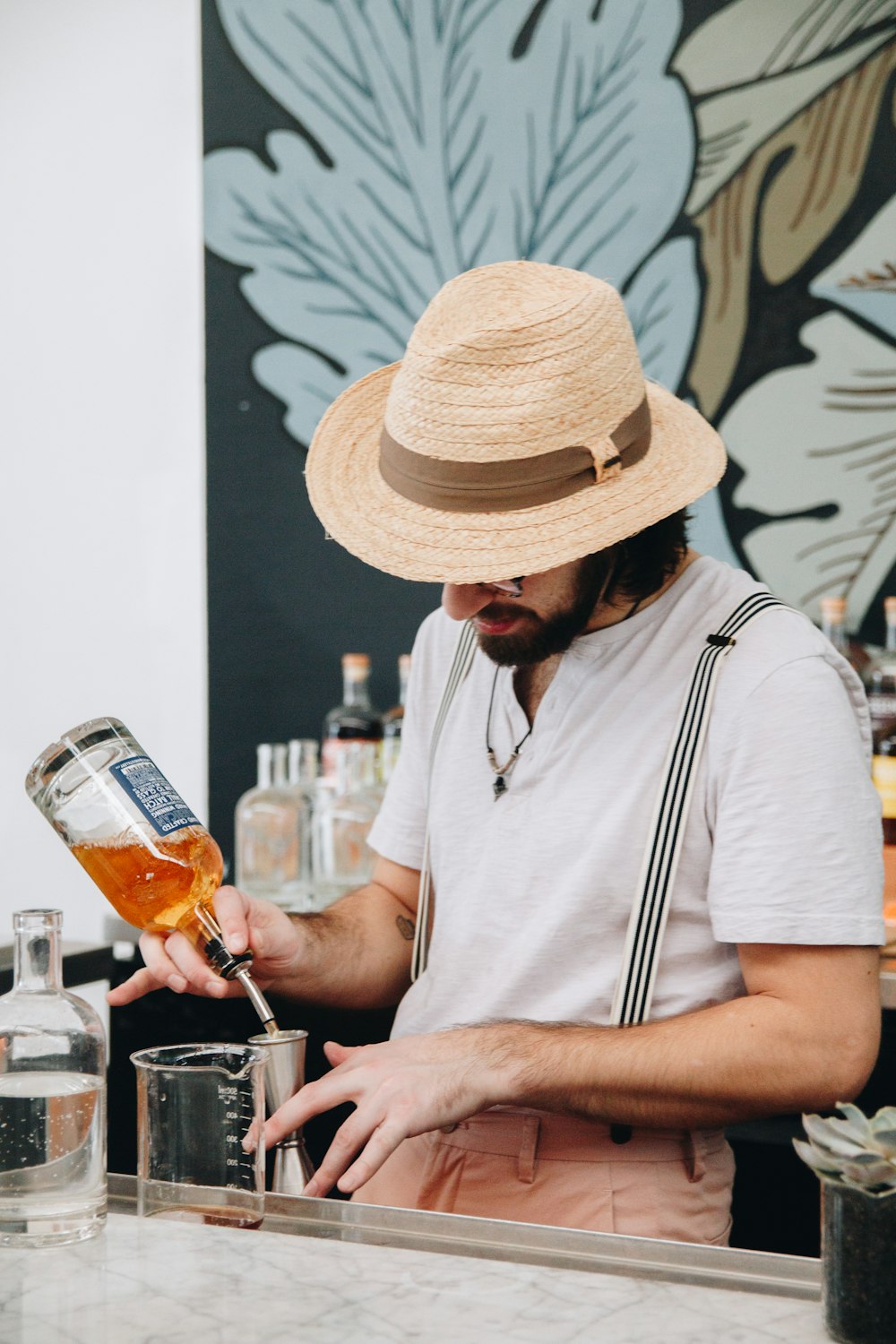 man in white shirt holding clear glass bottle