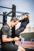 man in black t-shirt and blue denim jeans holding black smartphone