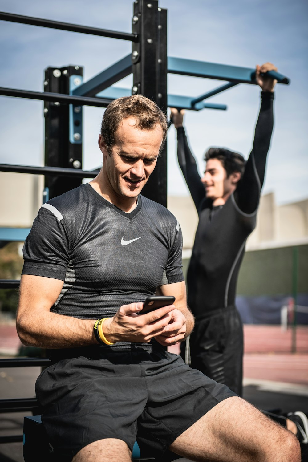 man in black nike crew neck t-shirt and black pants sitting on bench