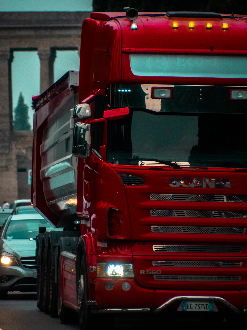 Truk HGV merah melaju di lalu lintas perkotaan di samping mobil