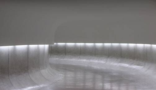 Minimalist immersive space with soft beige and gold lighting, evoking calm and slow movement.