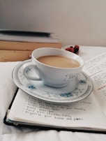 An elegant cup of tea beside a notebook filled with handwritten quotes.