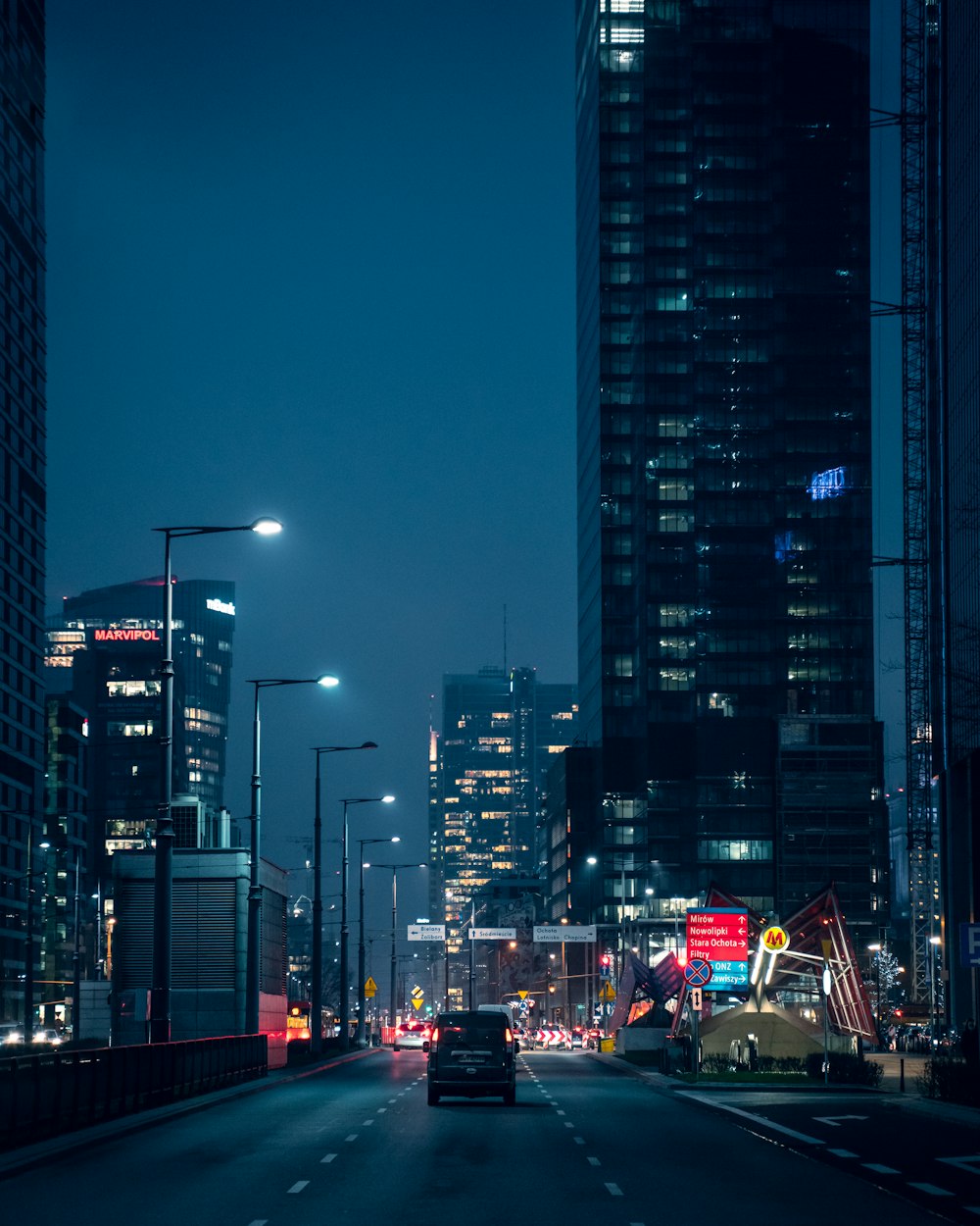 cars on road near high rise buildings during night time