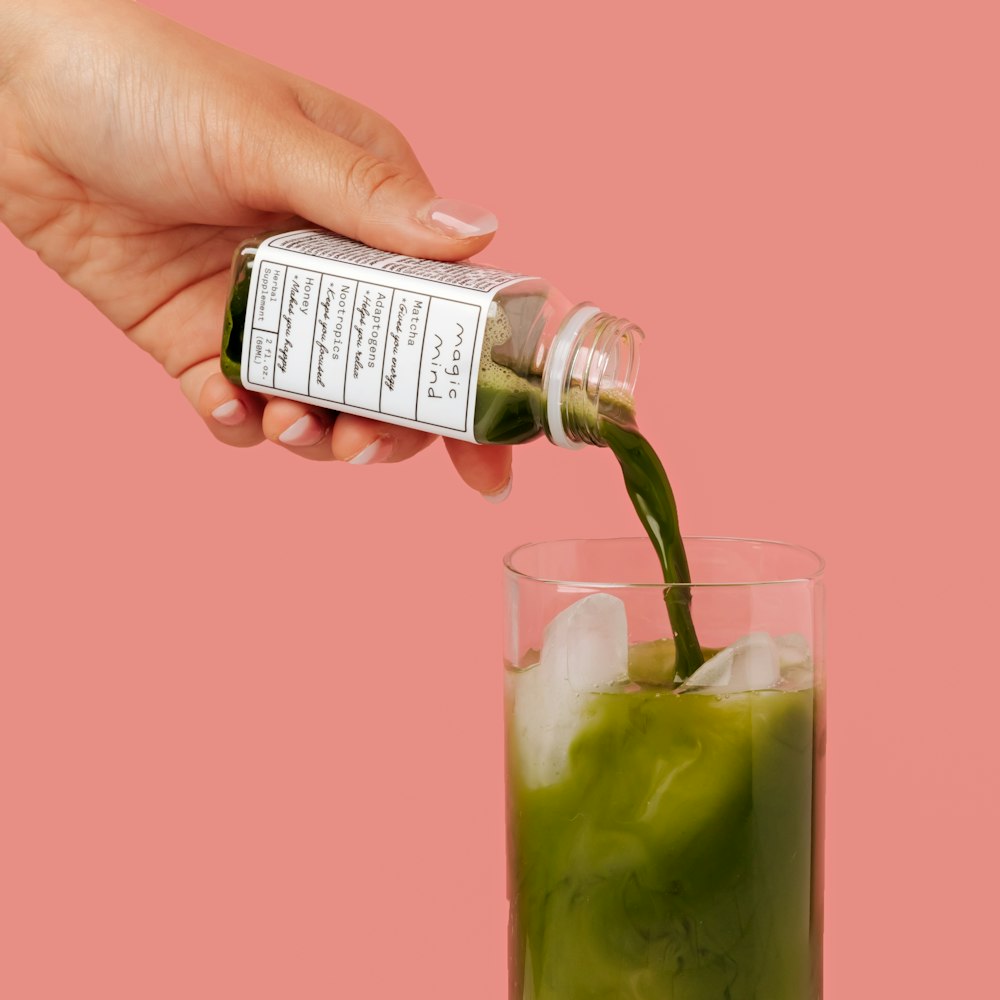 pessoa segurando copo transparente com líquido verde
