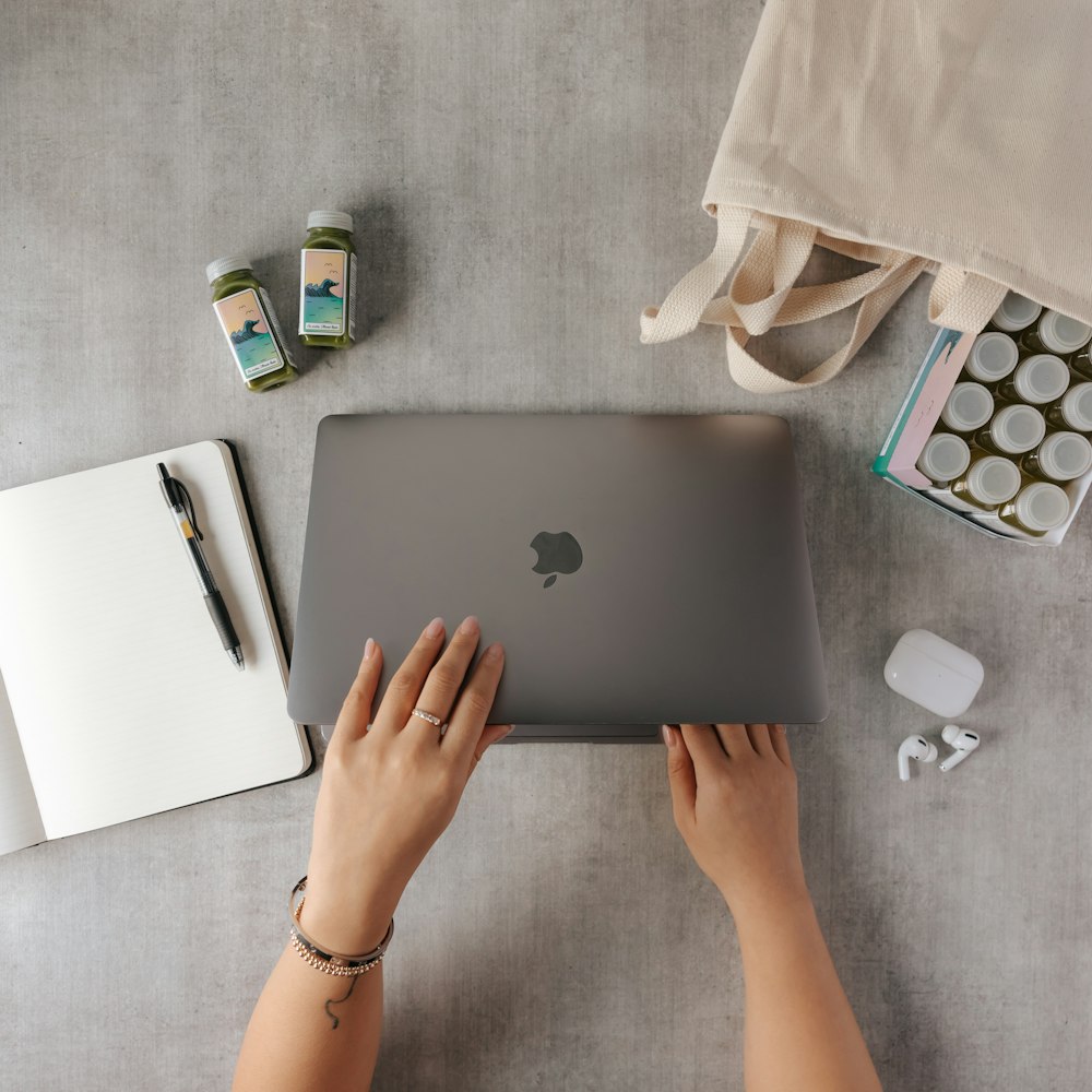 person using silver macbook on white table