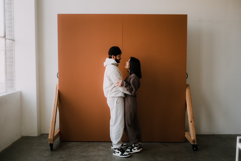 Hombre y mujer besándose frente a una pared marrón