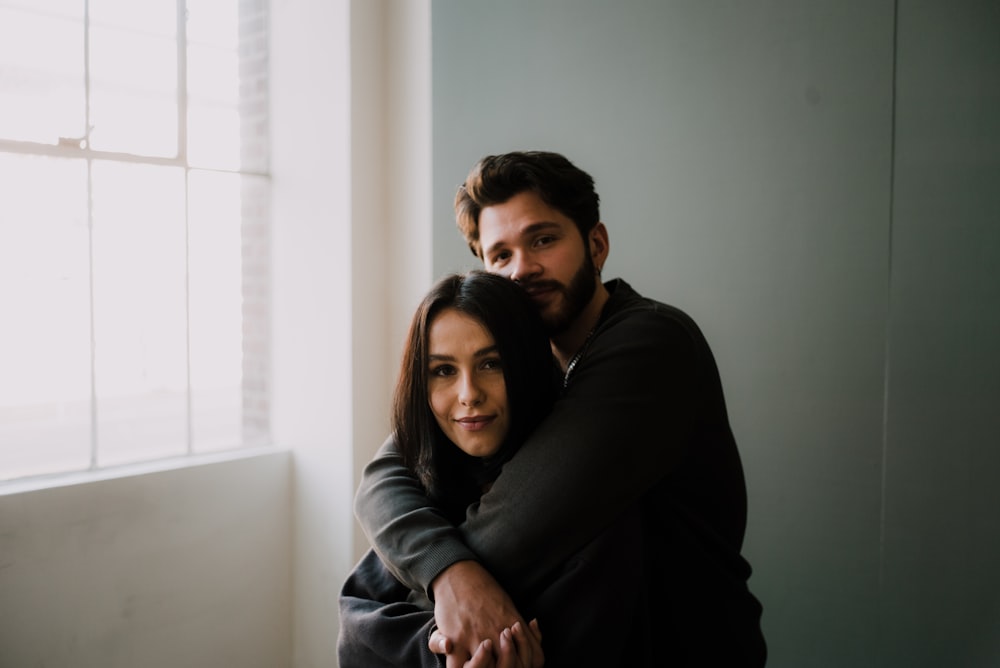 man in black sweater hugging woman in black long sleeve shirt