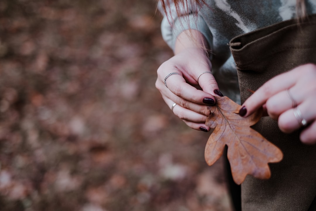 woman in gray jacket holding brown leaf