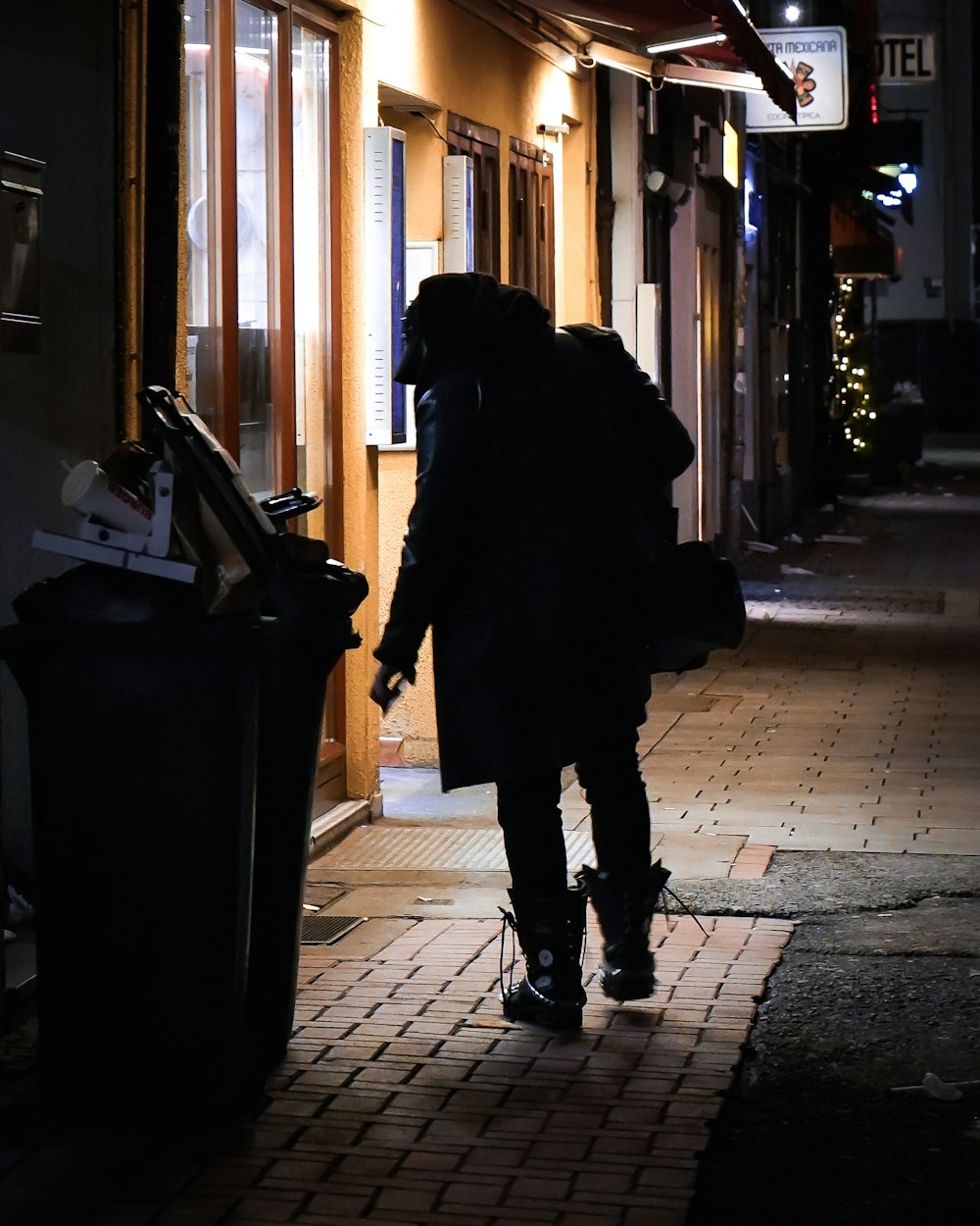 woman in black coat standing on sidewalk during daytime