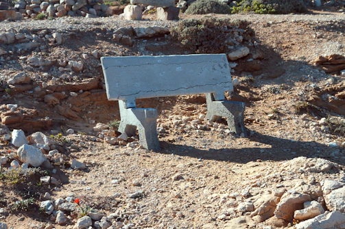 A rugged Texas-shaped concrete stone resting on a wooden workbench with sunlight streaming in.