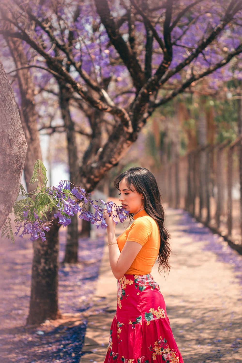 紫の花を持つ赤と白の花柄のドレスを着た女の子