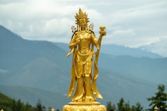 gold statue of man holding book