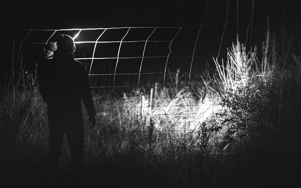 man in black jacket standing near fence