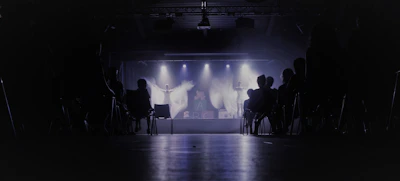 A vibrant scene from a recent No Notes Theatre Co. production, actors mid-performance under warm stage lights.