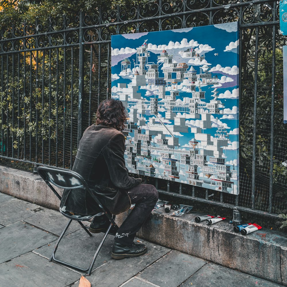 man in black jacket sitting on black chair looking at city buildings during daytime