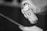 A hand is holding and using an aerosol spray can, applying it to an unseen surface. The can has visible branding and text.