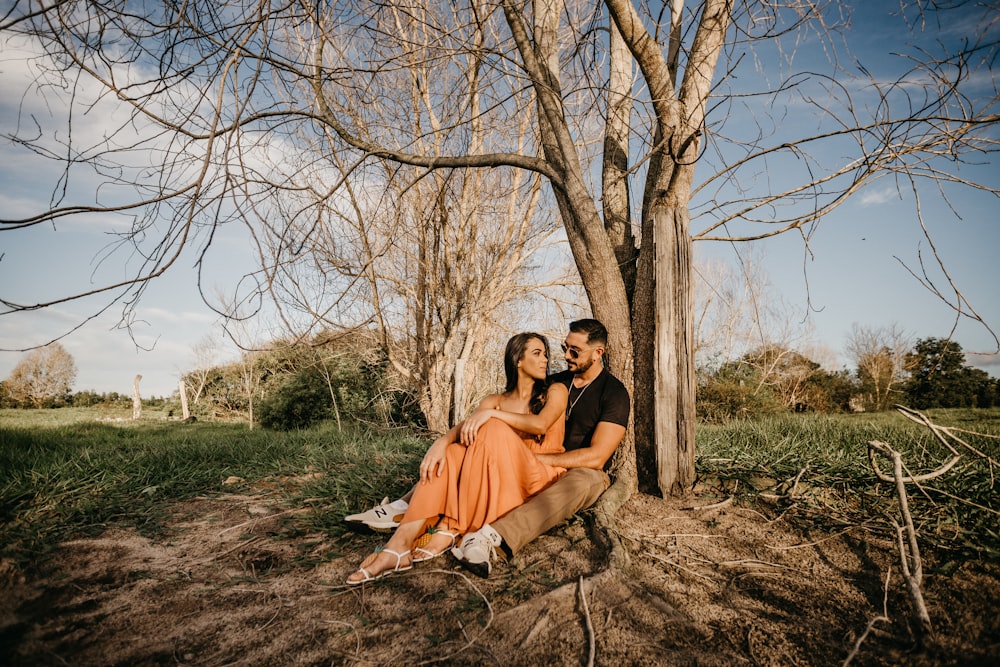 couple sitting on brown tree trunk during daytime