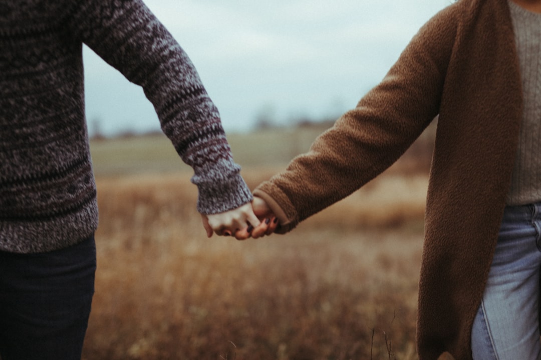 person in gray long sleeve shirt holding hands with woman in black long sleeve shirt