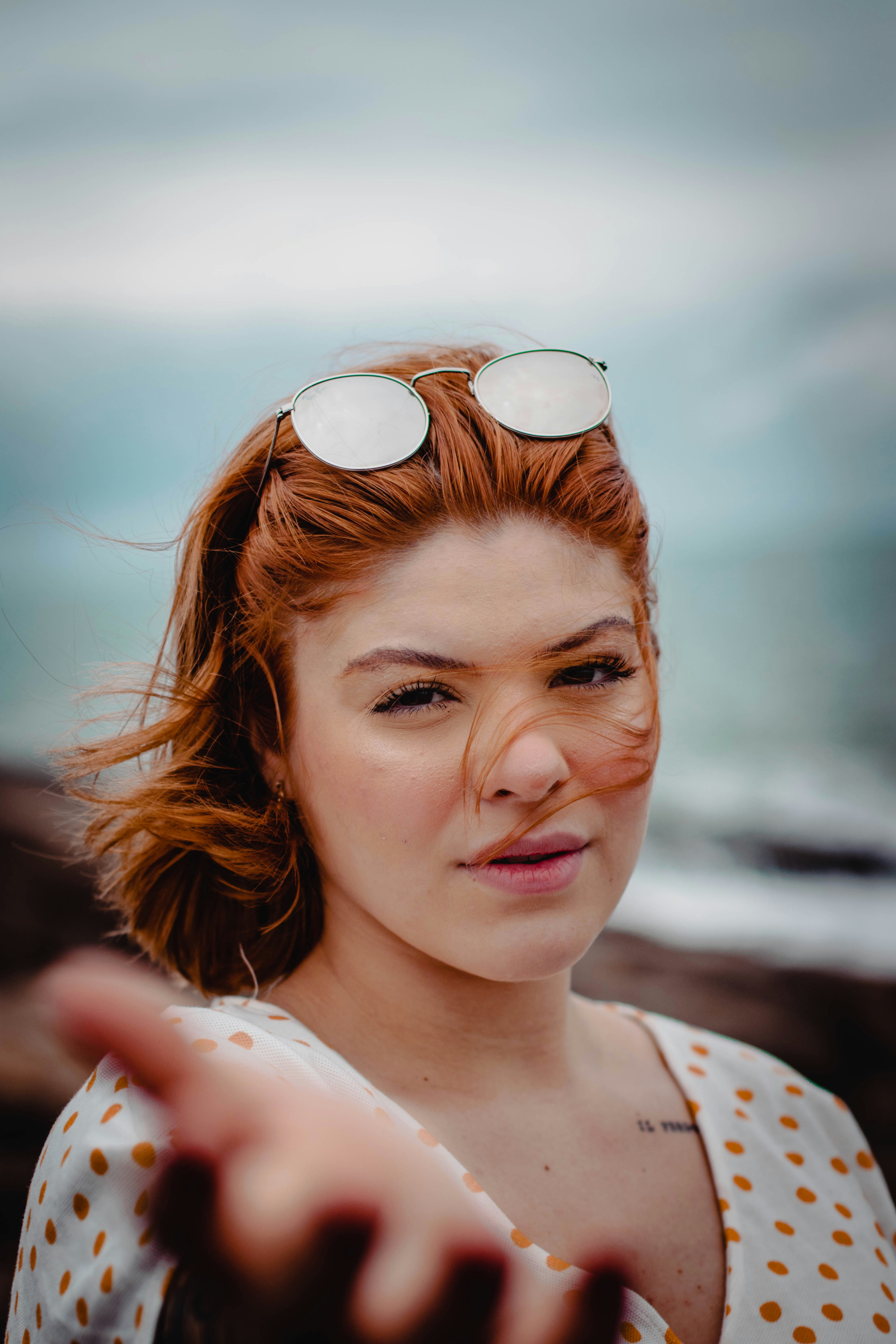 woman in white and blue floral shirt wearing brown sunglasses
