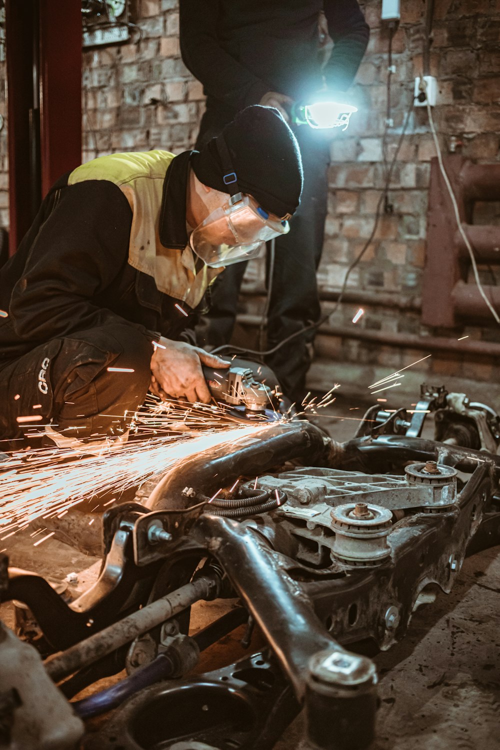 man in black jacket and yellow helmet holding black car engine