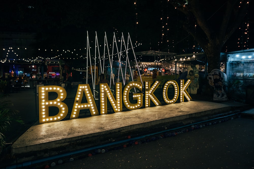 a sign that says bangkok lit up at night
