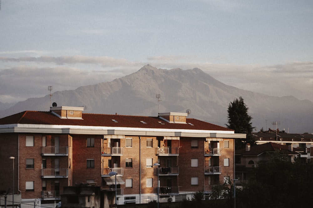 brown and white concrete building near green trees and mountain during daytime