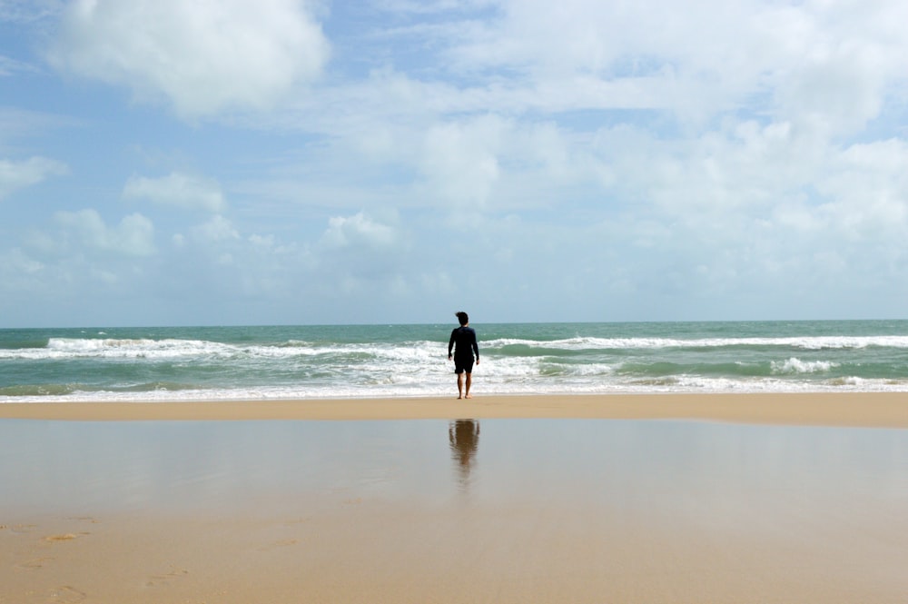 man in black jacket standing on seashore during daytime