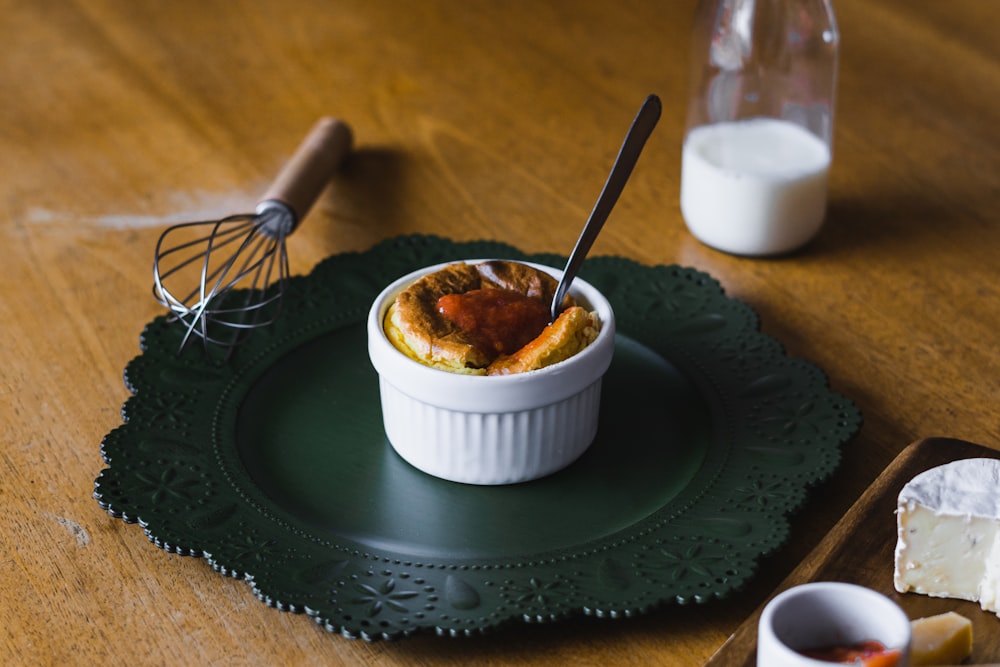 white ceramic bowl with stainless steel spoon on green round plate