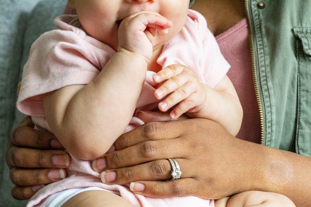 person in silver ring holding baby in white onesie