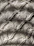 Close-up of intricate macramé knots hanging against a softly lit wall.