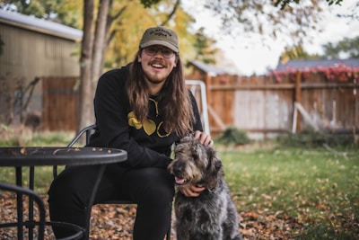 A smiling pet sitter gently petting a dog in a sunny backyard.