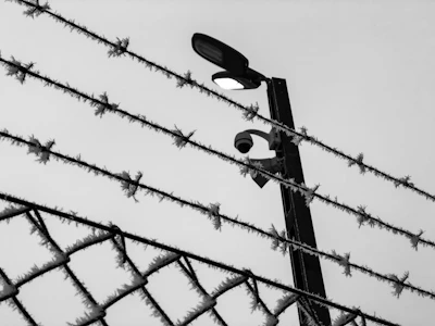 Close-up of electric fence wiring and a CCTV camera monitoring a commercial property at dusk.