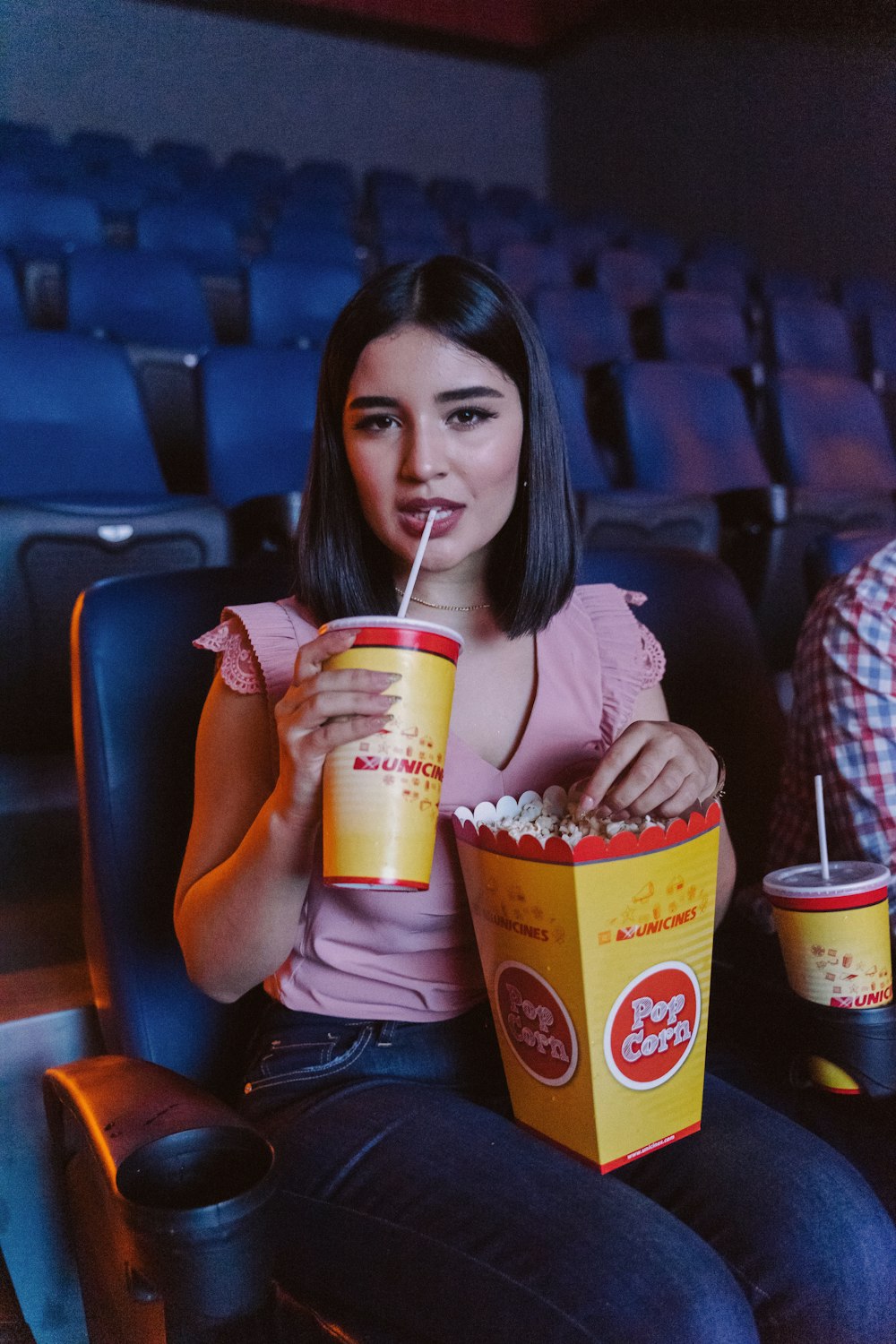 woman in pink shirt holding white and yellow disposable cup