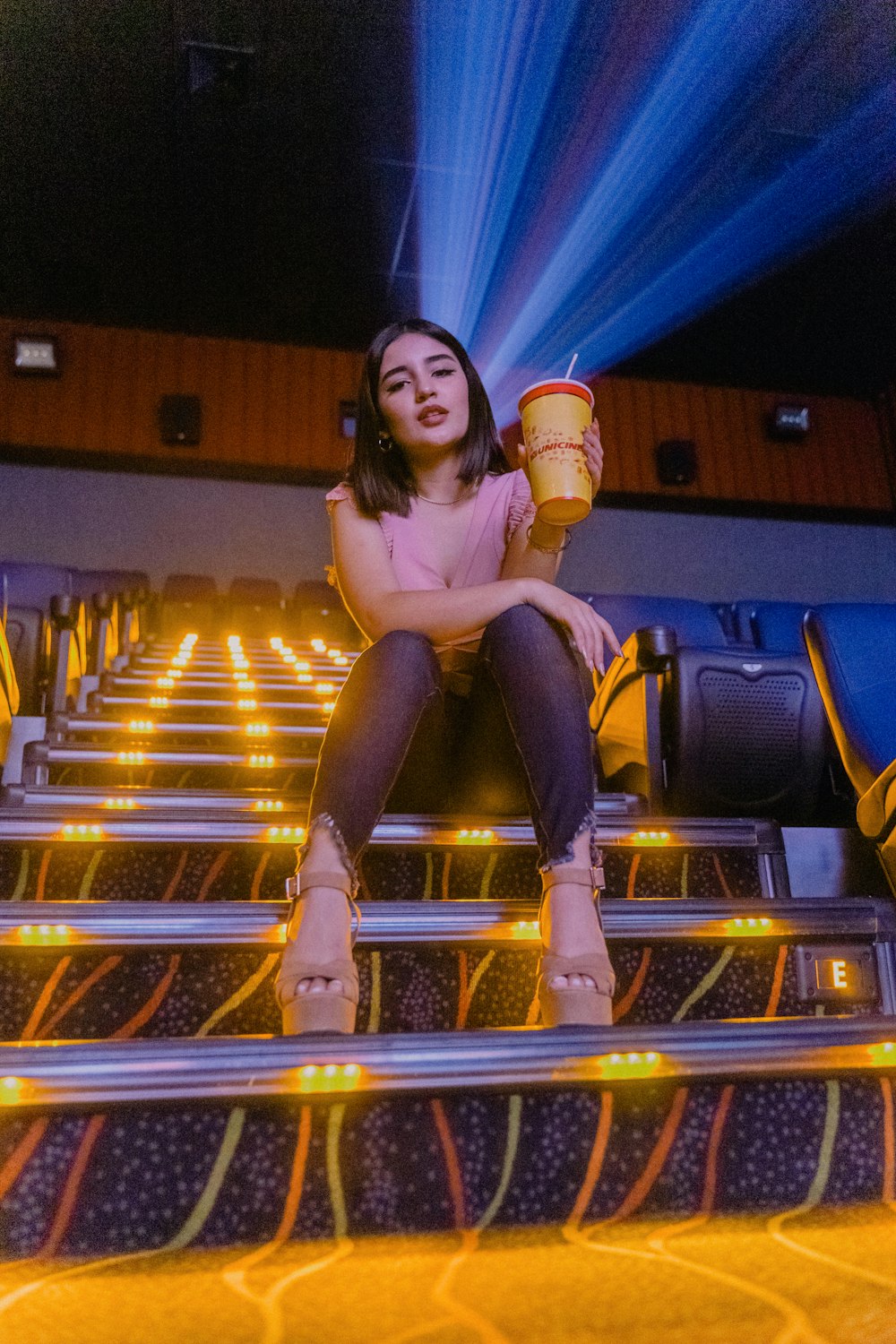 woman in white long sleeve shirt and blue denim jeans sitting on yellow metal bar