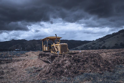 Bulldozer moving soil with a clear blue sky over agricultural land