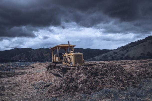 Powerful bulldozer moving earth on a vast terrain under a dramatic sky
