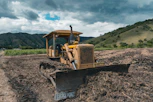 yellow and black heavy equipment on brown field under white clouds and blue sky during daytime
