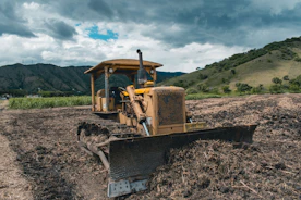 yellow and black heavy equipment on brown field under white clouds and blue sky during daytime