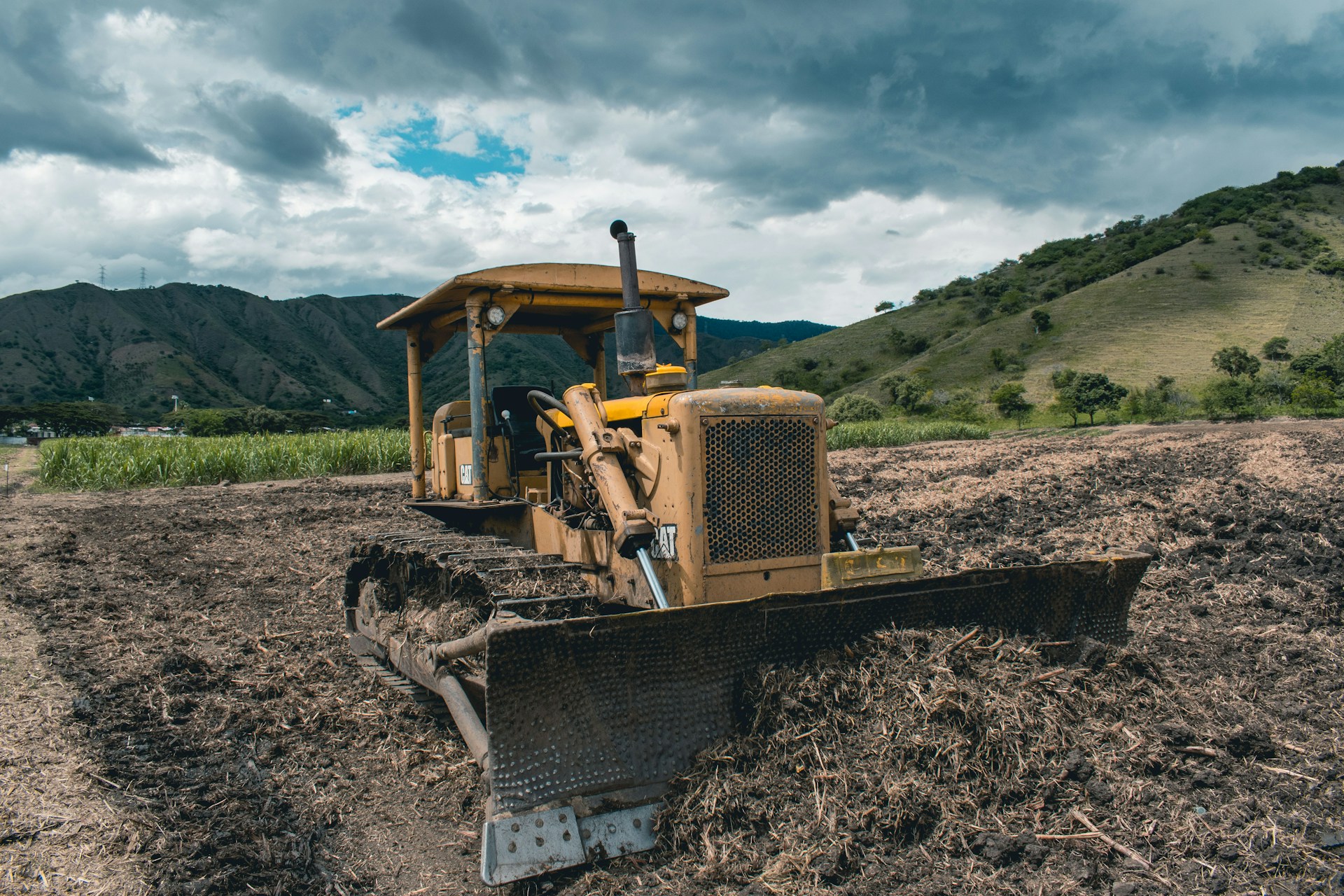 yellow and black heavy equipment on brown field under white clouds and blue sky during daytime
