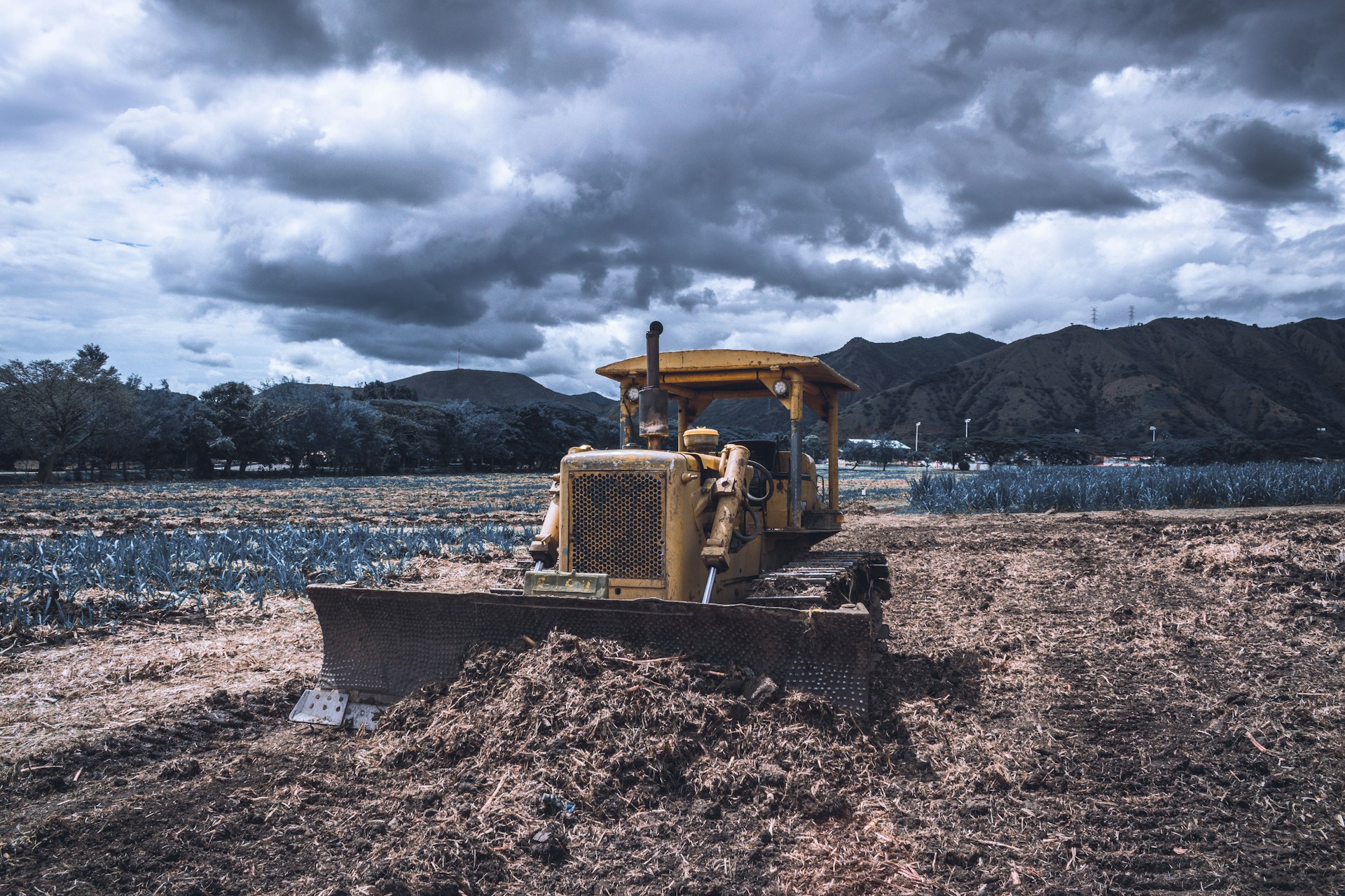 yellow and black heavy equipment on brown soil under cloudy sky during daytime